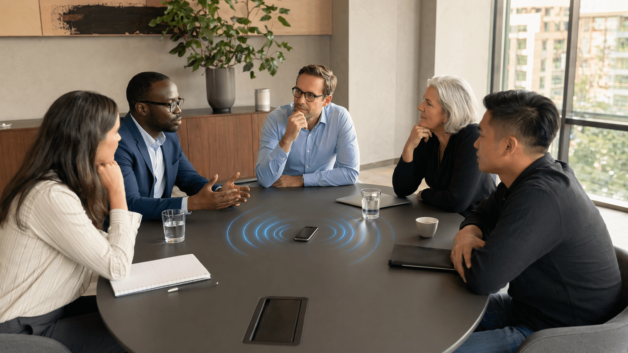 Professionals in a conference room with a smartphone recording the meeting on the table